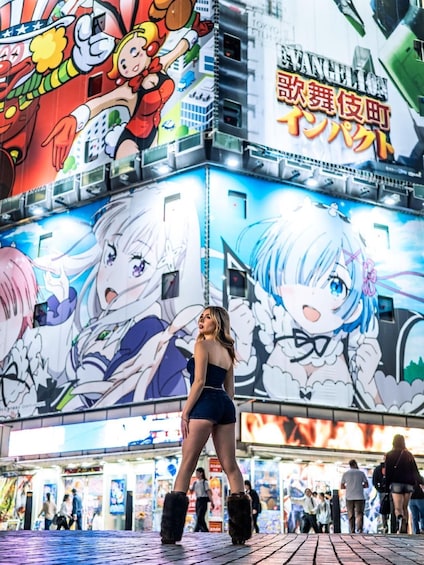 A person standing in front of a large anime-themed mural with characters and text in a foreign language. 1