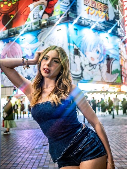 A person in denim attire posing in an urban setting with a vibrant mural in the background. 4