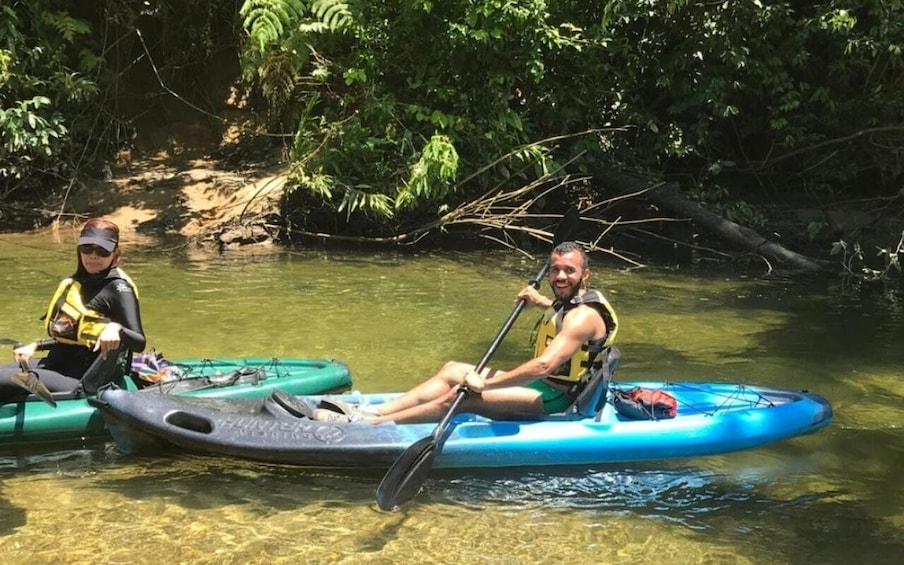 Two people kayaking on a calm river surrounded by dense greenery. 3