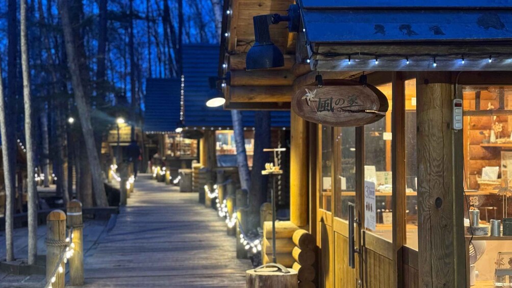 A wooden pathway lined with shops and illuminated by string lights. 2