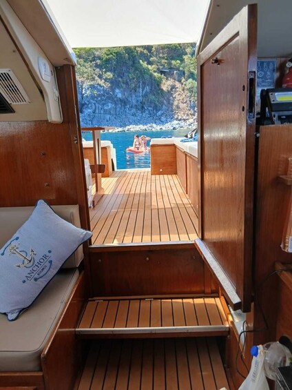 A wooden deck with a view of a rocky coastline and a boat in the water. 3