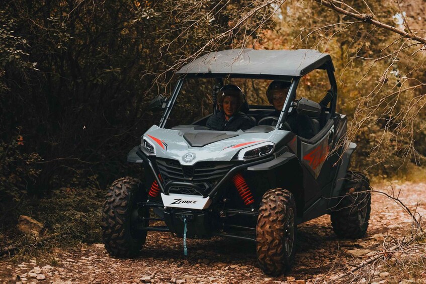 A ZForce off-road vehicle on a gravel path surrounded by trees. 2