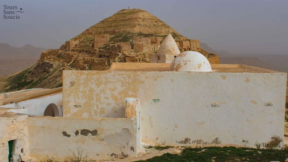 A historical site with ancient ruins, a dome, and a hilltop structure. 3