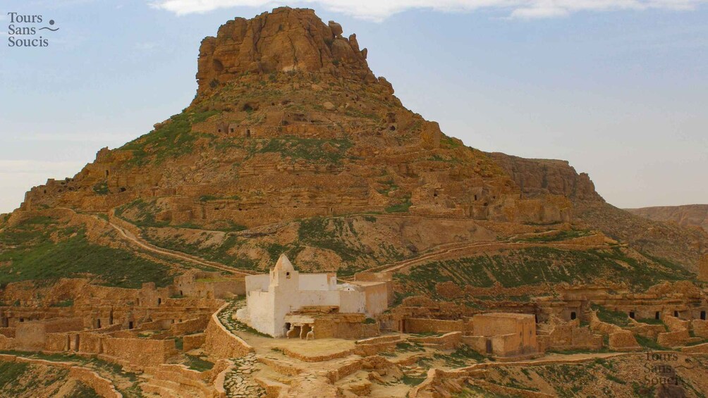A large rock formation with a white building at its base. 4