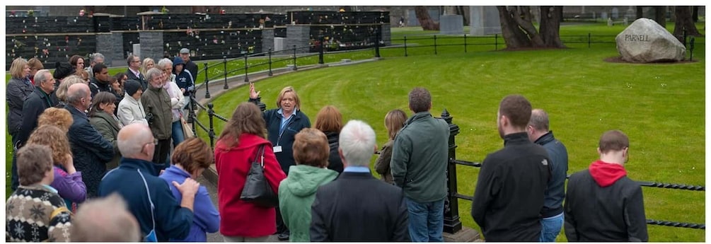 A group of people gathered in a park with a large stone monument labeled 'PARNELL' in the background. 2