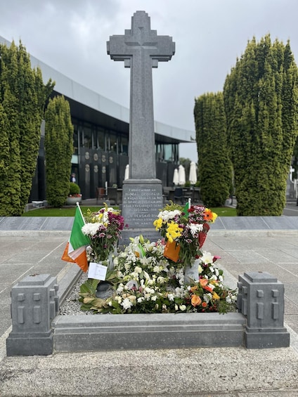 A memorial cross with flowers and an Irish flag. 2