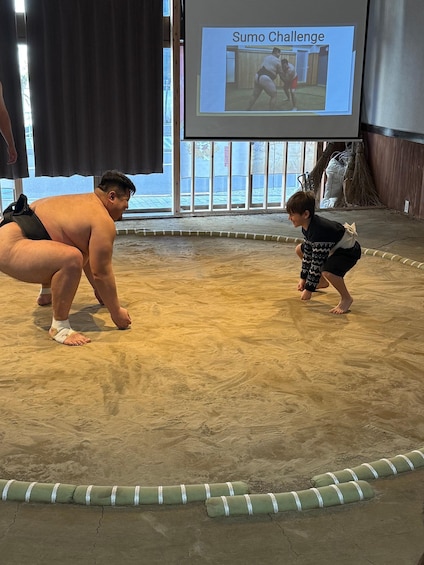 A sumo wrestler and a child in a ring with a 'Sumo Challenge' sign. 2