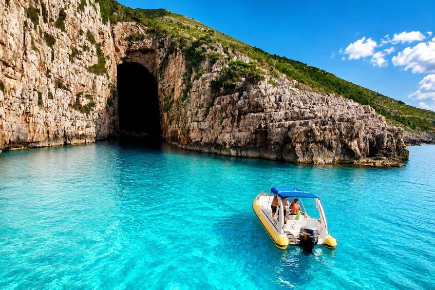 A boat near a rocky cave entrance with clear blue water. 1