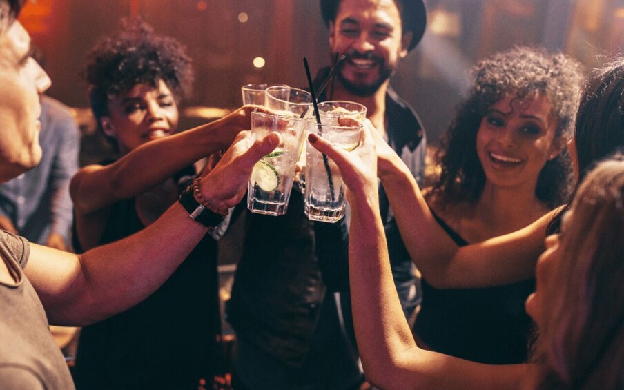 A group of people toasting with drinks in a dimly lit setting. 1