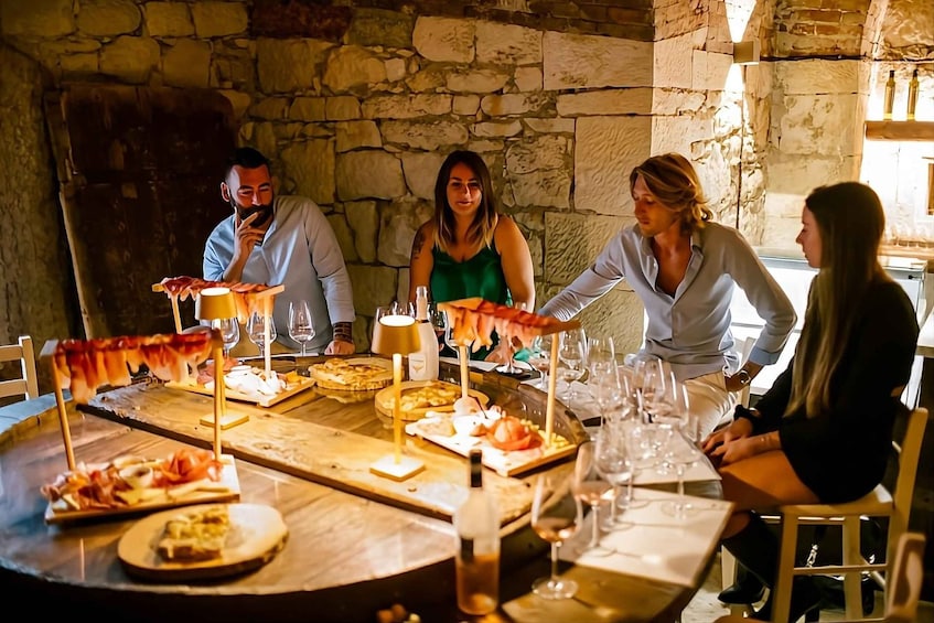 A group of people dining at a round table with various dishes and wine glasses. 4