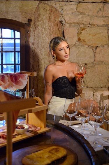 A person holding a glass of drink at a bar with a rustic stone wall background. 3