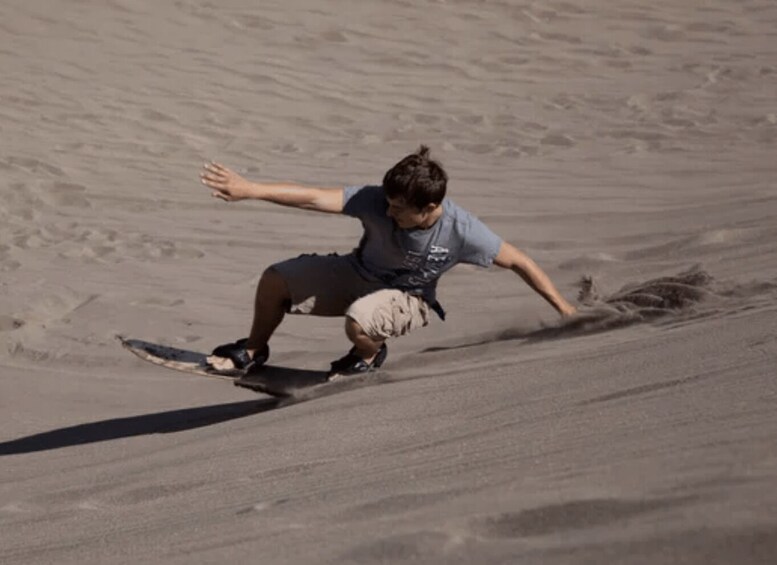 A person riding a skateboard down a sandy slope. 1