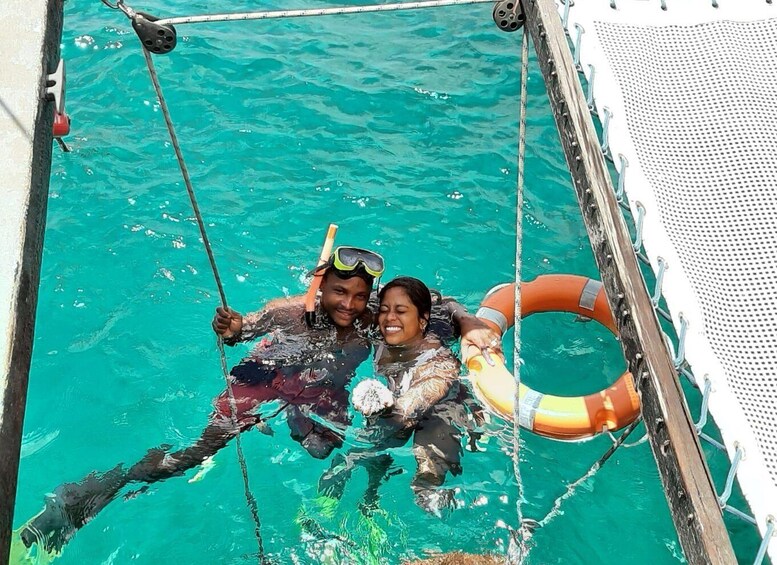 Two people snorkeling in a clear blue pool with a rope and a life ring. 4