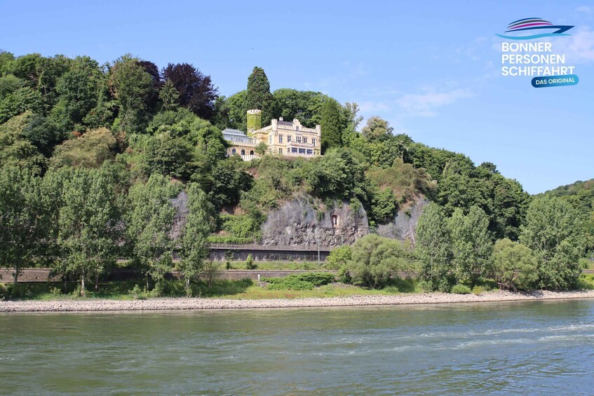 A large, historic house on a hill by a river. 2