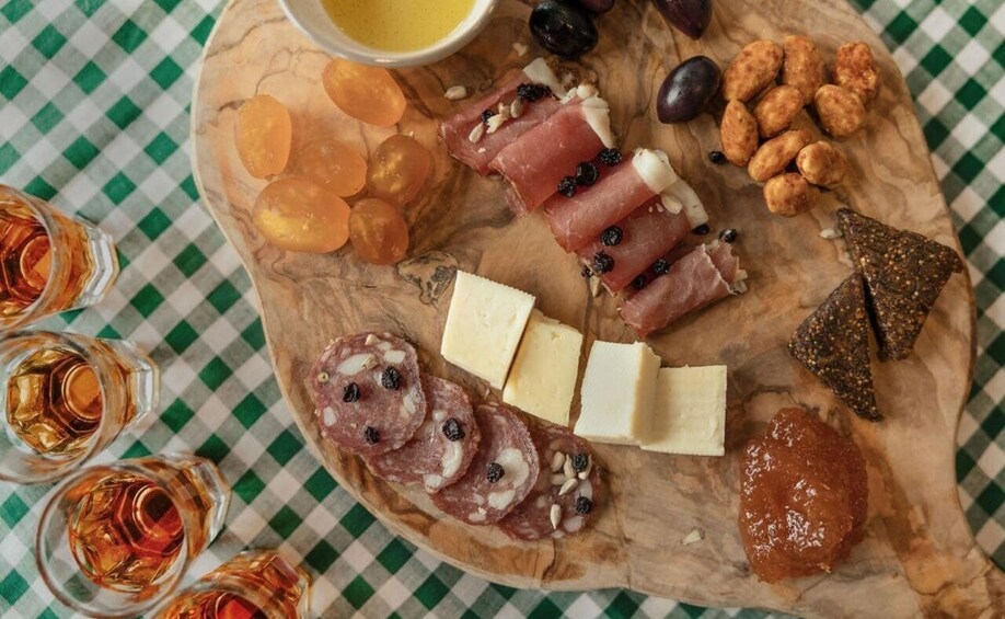 A charcuterie board with various meats, cheeses, nuts, and olives on a wooden board. 1