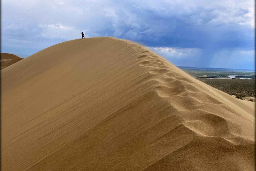 A large sand dune with a person standing at the top. 5