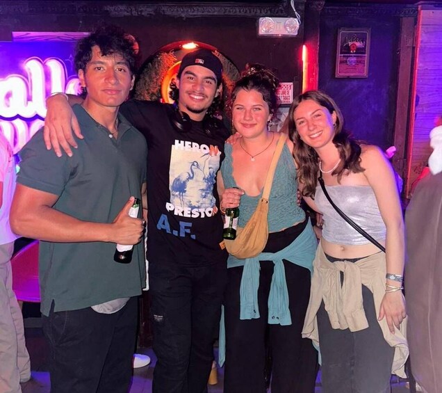 A group of people at a social event with a neon sign in the background. 4