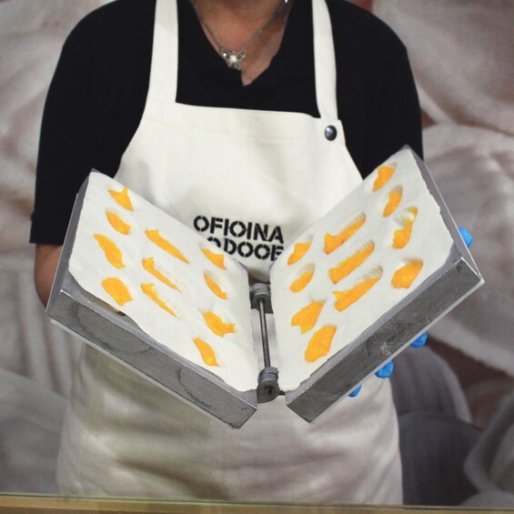 A person holding a white object with orange patterns and the text 'OFIOINA DOOEF' on it. 5