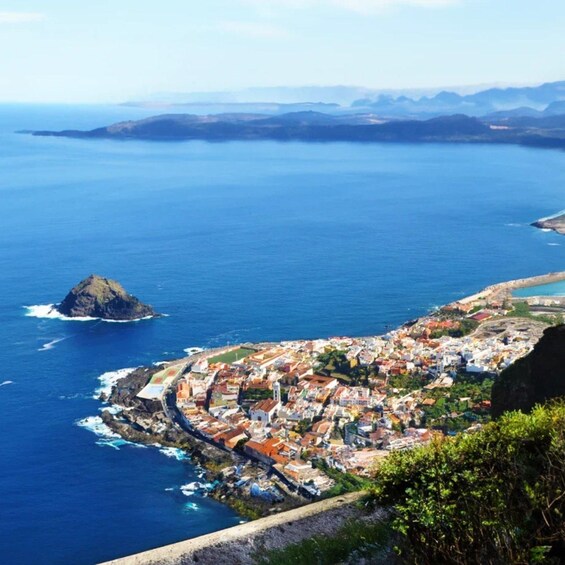 A coastal town with a prominent hill, a small island, and a clear view of the surrounding ocean and hills. 4