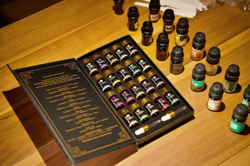 A collection of essential oils in small bottles, some in a box with labels, on a wooden surface. 4