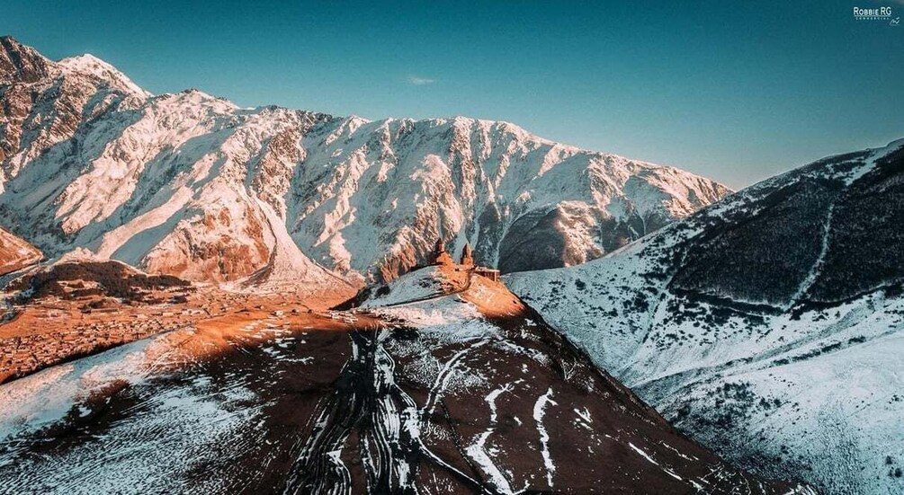 A snow-covered mountain range with a clear sky. 1