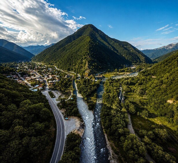 A river flowing through a valley with a mountain in the background and a road curving alongside. 3