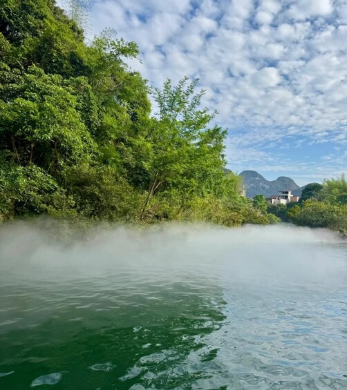 A river with mist rising from the water, surrounded by lush greenery and distant mountains. 5