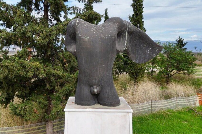A large elephant statue on a pedestal in a grassy area with trees and a fence in the background. 5