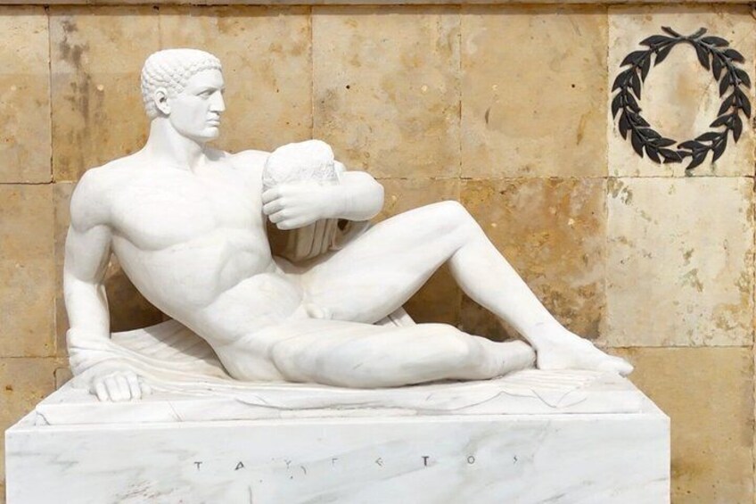 A marble statue of a reclining man with inscriptions on the base. 4