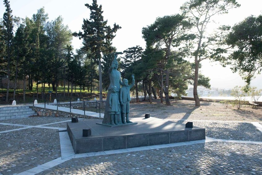 A statue of a man and a child in a park with trees and a stone pathway. 4