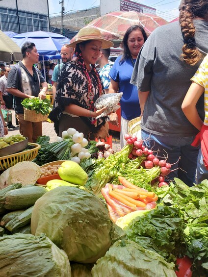 A bustling outdoor market with fresh produce and people shopping. 1