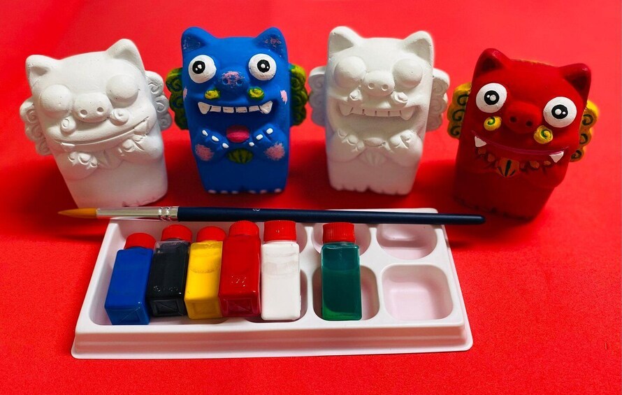 Four ceramic animal figurines, a paintbrush, and a set of paint bottles. 1