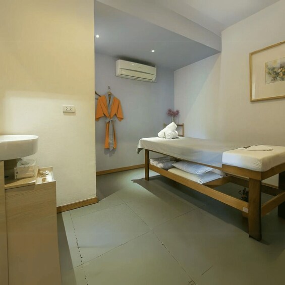 A room with a bed, a sink, an air conditioner, and a robe hanging on the wall. 3