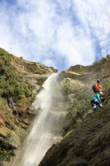 A waterfall cascading down a rocky cliff with hikers on the side. 5
