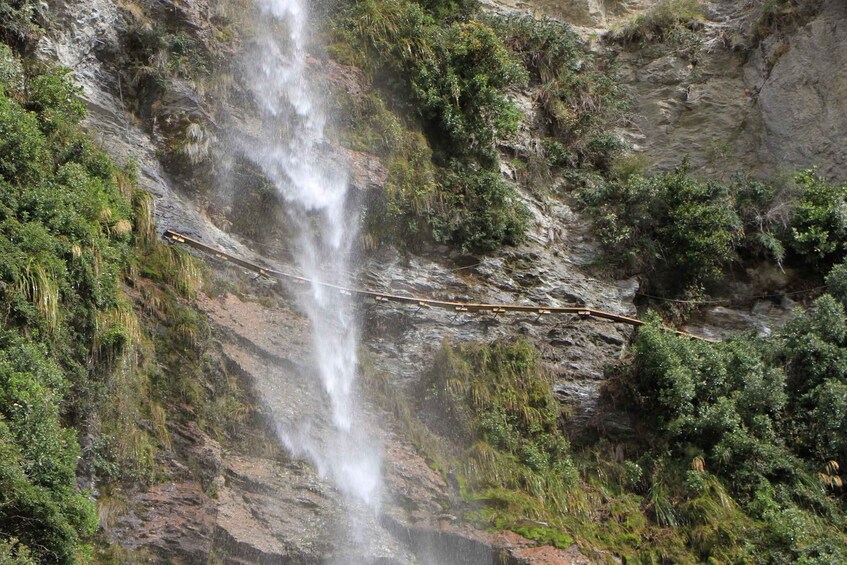 A waterfall cascading down a rocky cliff surrounded by dense greenery. 3