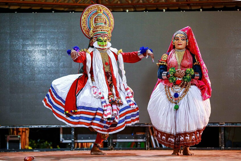 Two performers in traditional costumes with elaborate headdresses and jewelry, performing on a stage. 3
