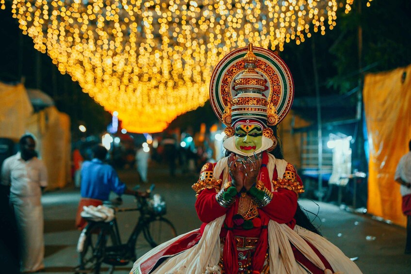A person in traditional attire with a large headdress, standing in a street with festive lights overhead. 4