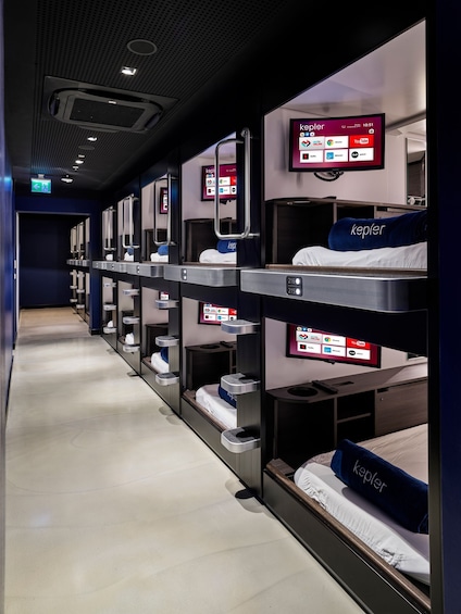 A train carriage with bunk beds, each with a Kepler-branded pillow, and a digital screen displaying Kepler app icons. 2