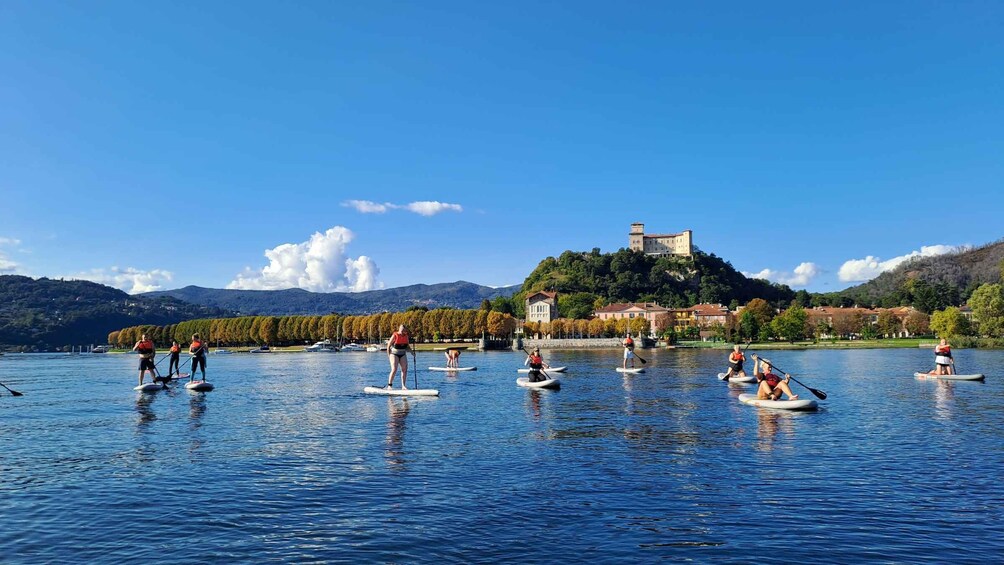 People paddleboarding on a calm lake with a castle on a hill in the background. 5