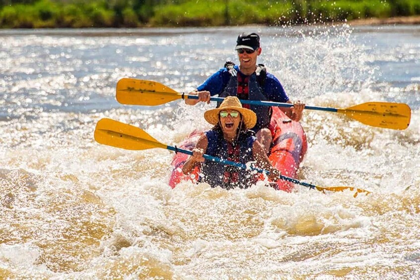 Two people kayaking on a river with splashing water. 1