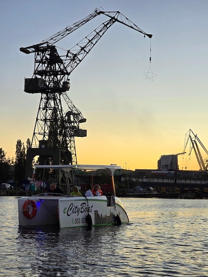A boat with 'eCityBoat' and a phone number on its side, docked near a large crane structure. 2