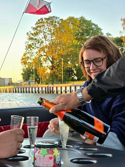 A person pouring champagne into a glass on a boat. 3