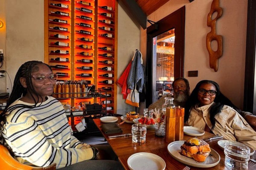 A restaurant interior with a wine rack, a wooden wall decoration, and a table with food and drinks. 4
