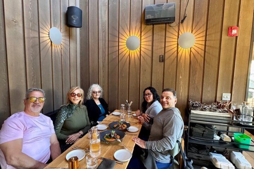 A group of people dining at a wooden table with a sunburst light fixture above. 3