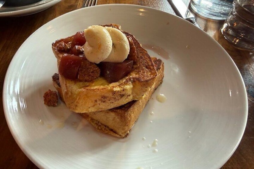 A plate of French toast with fruit and a dollop of whipped cream. 4