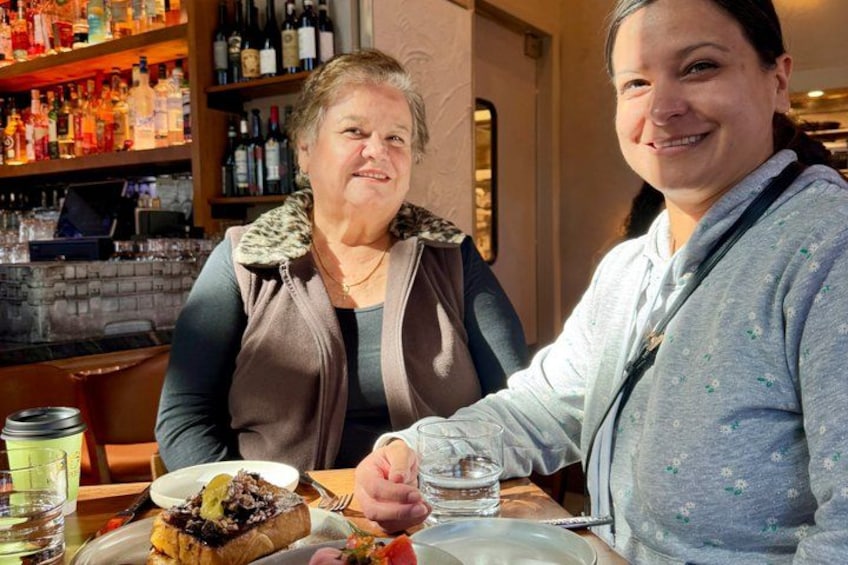 Two people sitting at a table with a dessert and drinks. 1