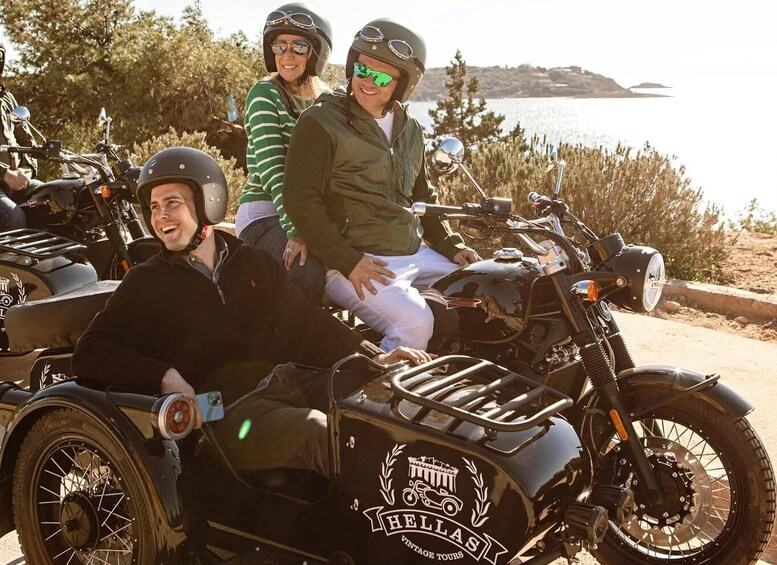 A vintage motorcycle with a sidecar, a person in a green jacket, and a person in a striped sweater. 1