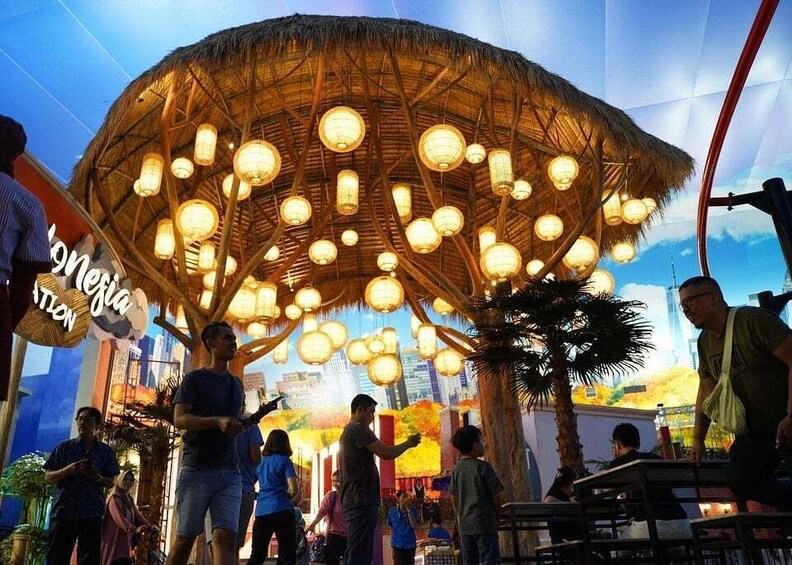 A thatched-roof structure with hanging lights, surrounded by people. 1