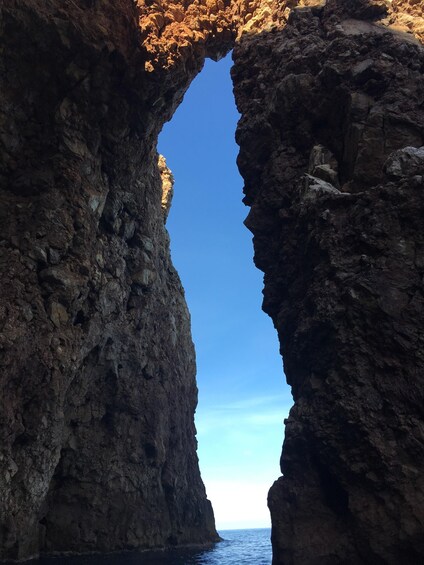 A natural rock formation with a clear blue sky visible through a narrow opening. 4
