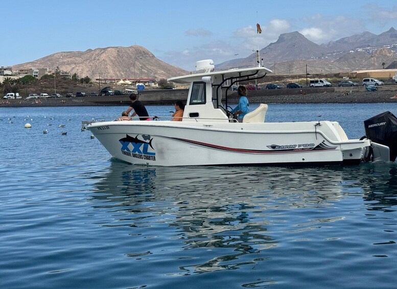 A boat named 'Tenerife Anglers Charter' on calm water with mountains in the background. 5